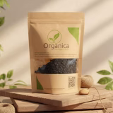 Packet of Organica Premium Organic Black Raisins (Kali Kishmish) displayed on a rustic wooden stand with natural lighting. Eco-friendly kraft paper pouch showing fresh, sun-dried black raisins through the window