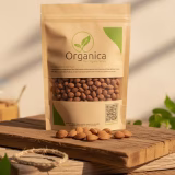 A packet of Organica The Organic Store premium apricot kernels sitting on rustic wooden planks in a sunlit natural setting, showcasing organic dry fruits from Pakistan.