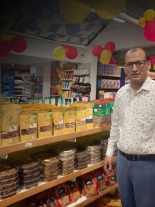 Retail store representative standing next to a fully stocked shelf of Organica premium dry fruits, including Energy Booster mix and dried apricots.